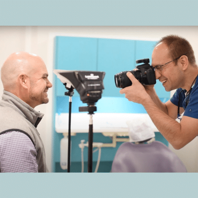 Dr. Dounis taking a photo of a patient's teeth, representing how often to visit periodontist