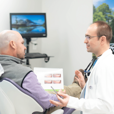 Dr. Dounis talking to a patient, representing comprehensive periodontal treatments