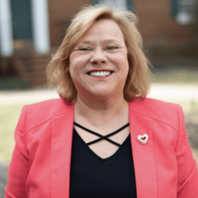 Older female patient smiling with her new full arch dental implants at synergy periodontics & implants